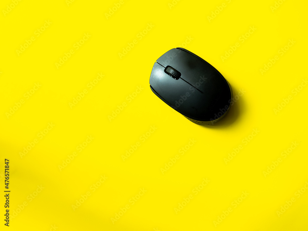 Black computer mouse with yellow background Black computer mouse with yellow background