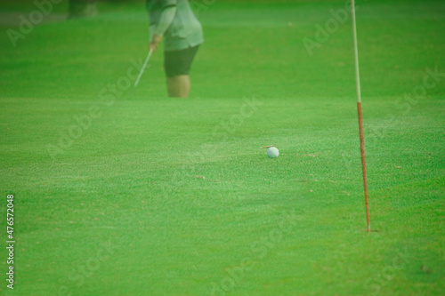 golfer putting green ball into hole