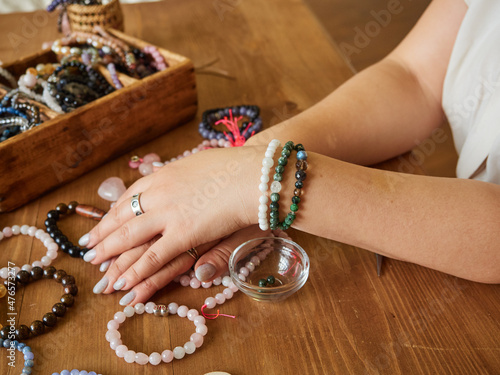Several bracelets made of natural stones on the hands of a craftswoman. Handmade concept