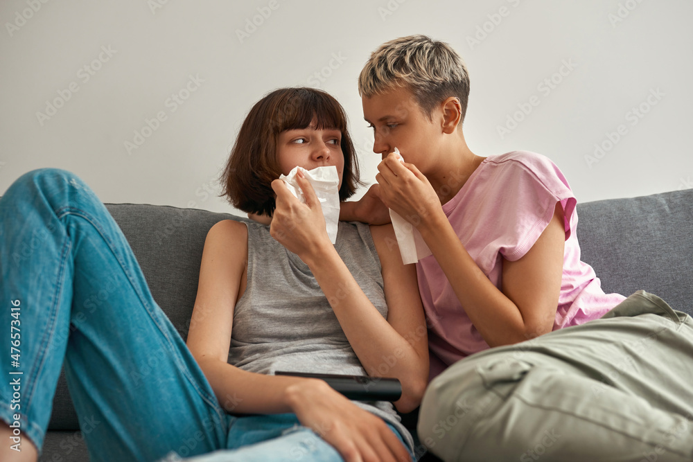 Young sad lesbians watching TV and crying on sofa Young sad lesbians watching TV and crying on sofa