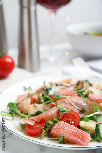 Delicious pomelo salad with prosciutto served on white marble table, closeup. Space for text