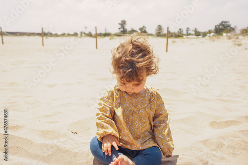 Little girl playing with sand at the beach photo
