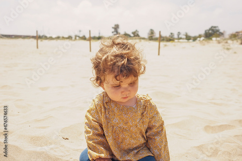Little girl playing with sand at the beach photo
