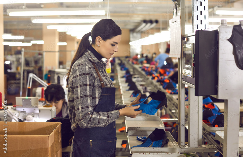 Side view of shoe factory worker standing in big sewing workshop and  checking quality of unfinished details of future sneakers. Mass footwear  manufacturing concept Photos | Adobe Stock