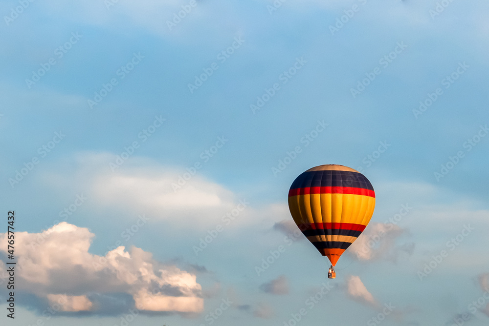 a brightly colored balloon in the blue sky against a background of white clouds a brightly colored balloon in the blue sky against a background of white clouds