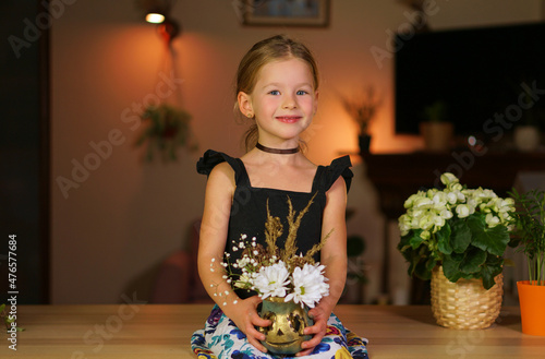 Beautiful girl hold pumpkin with flowers for halloween. child smiles and laughs in frames on an orange background. Cut jack head out of pumpkin with your own hands. Have fun as a child for holiday.