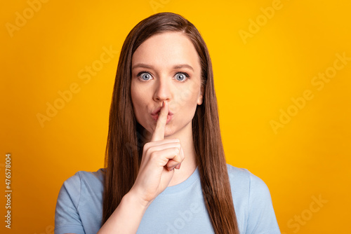 Photo of young charming woman cover lips finger shh keep secret confidential isolated over yellow color background
