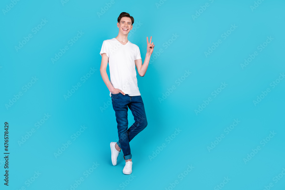 Full size photo of young cheerful man good mood show fingers peace cool v-symbol isolated over blue color background Full size photo of young cheerful man good mood show fingers peace cool v-symbol isolated over blue color background