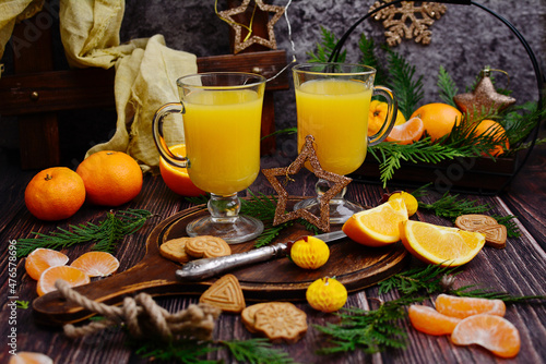 Fresh orange juice in glass glasses on the background of New Year's decor. Cozy winter composition