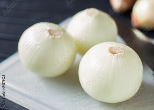 An image selected close-up focus heap onion white peeled spice taste food ingredient placed on the chopping board for eating.