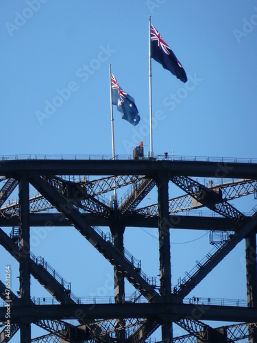 Steel structure of Sydney Harbour Bridge with two Australian flags on top under a blue sky, Sydney, New South Wales, Australia © Jens