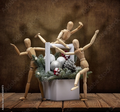 Wooden men gestalta celebrate New Year and Christmas with a merry company with a Christmas tree, toys, on a wooden table and an artistic background. photo