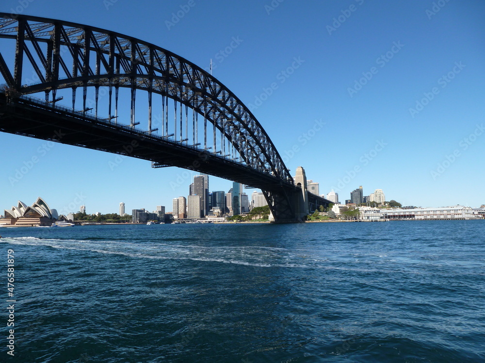 Sydney Harbour Bridge with Opera House and skyline in the background under a blue sky, Sydney, New South Wales, Australia