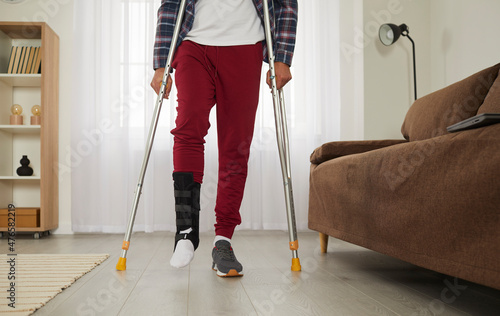 Foto Man with broken leg at home tries to walk with crutches and succeeds in rehabilitation