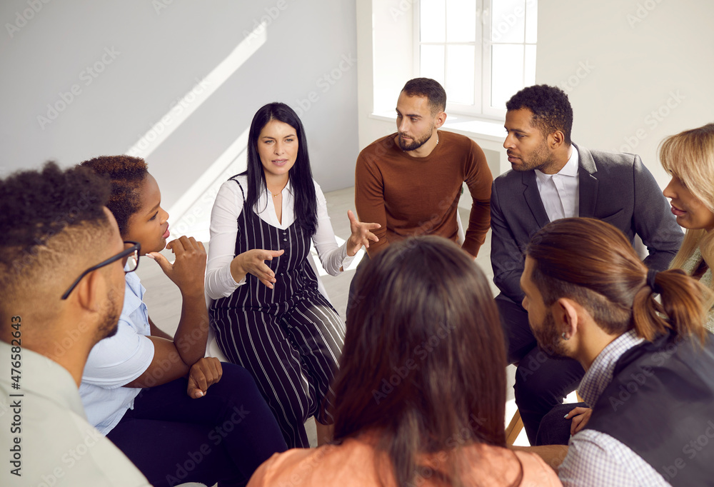 Diverse businesspeople sit in row at office meeting brainstorm discuss company business idea or plant together. Multiracial group of employees talk engaged in teambuilding. Teamwork concept. Diverse businesspeople sit in row at office meeting brainstorm discuss company business idea or plant together. Multiracial group of employees talk engaged in teambuilding. Teamwork concept.