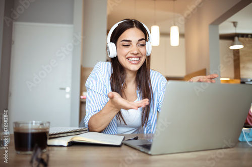 Young woman talk on video call at the table using headphones