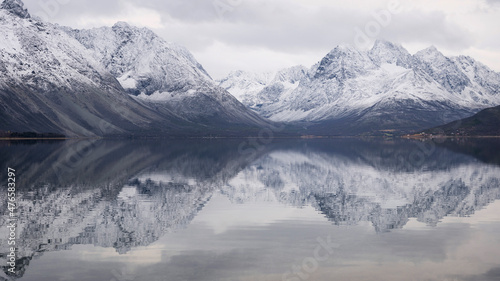 The peaks and glacier valleys of the Lyngen Alps reflected in the calm fjord waters - norther Norway