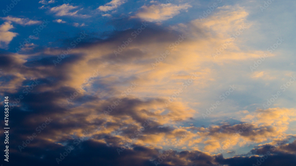 Passages nuageux pendant le coucher du soleil.  Les nuages arborent une teinte orangée