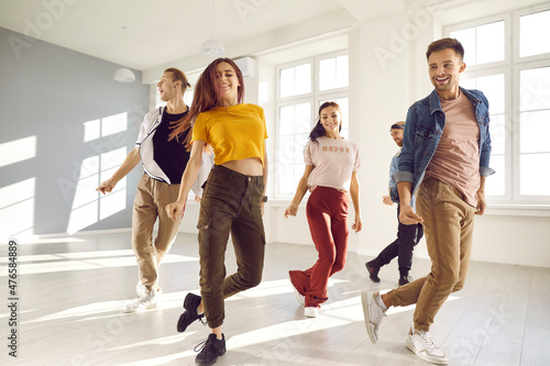 Happy young people dance in causal clothes in studio prepare for concert. Smiling energetic millennial diverse dancers training performing together at class or lesson. Hobby and entertainment.