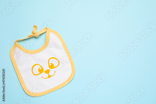New baby bib on light blue background, top view. Space for text photo