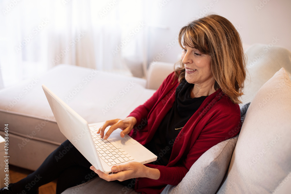 Naklejka premium Smiling senior woman using tablet at home