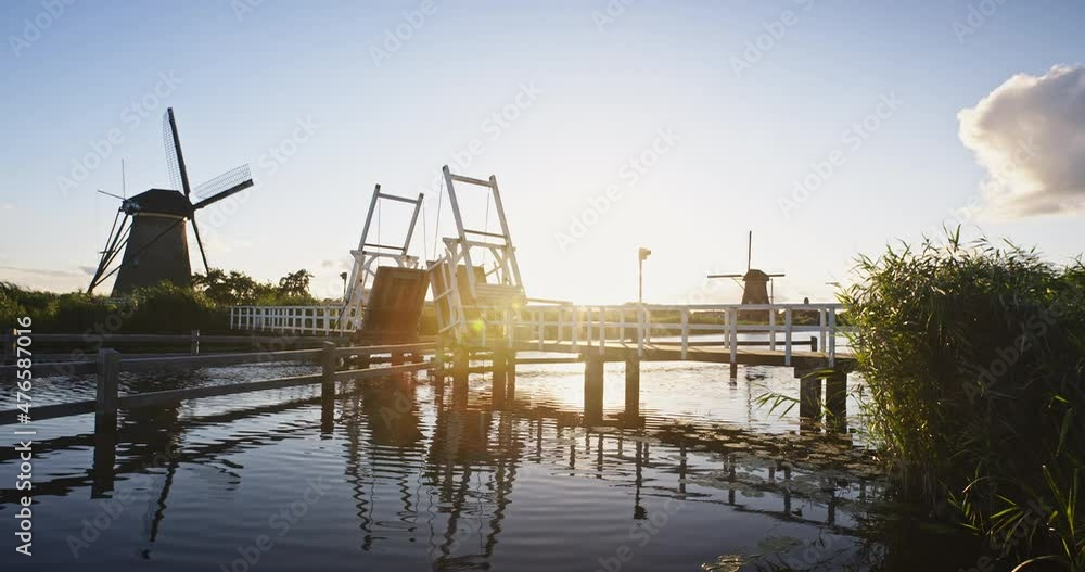Summer scenery at Kinderdijk, The Netherlands - a water canal with a historic windmill on a sunny day. Slow motion shot. Summer scenery at Kinderdijk, The Netherlands - a water canal with a historic windmill on a sunny day. Slow motion shot.