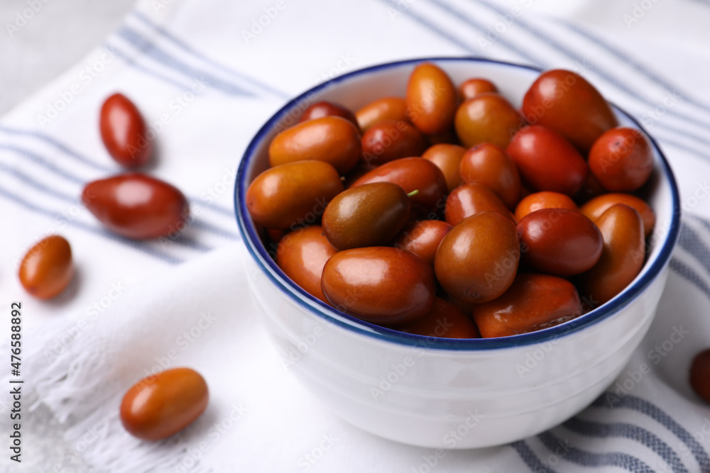 Fresh Ziziphus jujuba fruits with bowl and napkin on table, closeup Fresh Ziziphus jujuba fruits with bowl and napkin on table, closeup