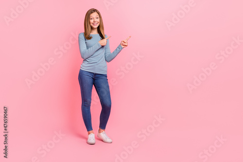 Full length body size view of attractive cheerful girl demonstrating copy space ad isolated over pink pastel color background