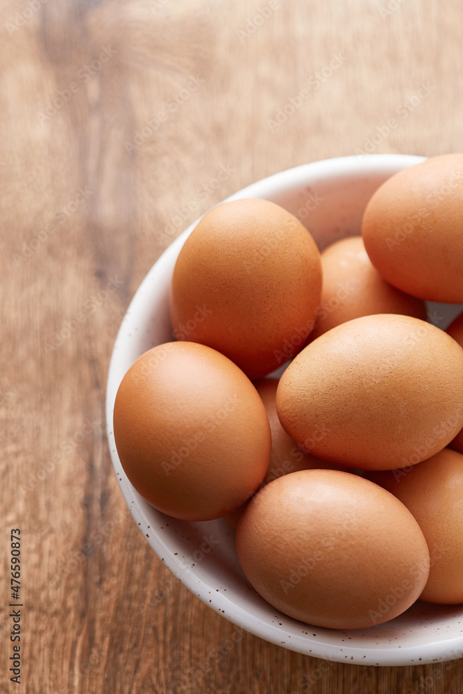 Eggs in a bowl. Brown eggs on a wooden background viewed from above. Top view Eggs in a bowl. Brown eggs on a wooden background viewed from above. Top view