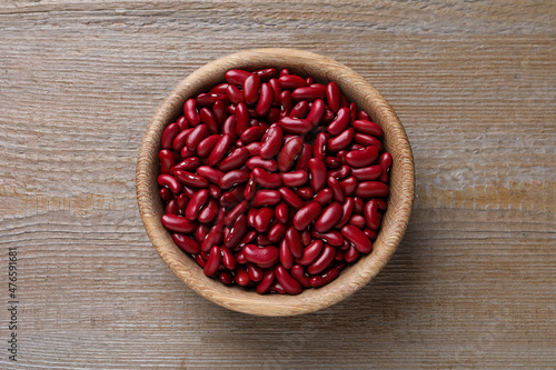 Raw red kidney beans in bowl on wooden table, top view