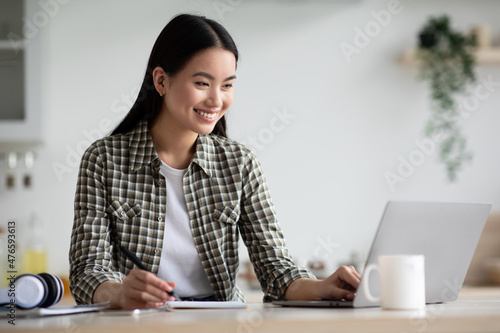 Fotografie, Obraz Smiling asian woman student using laptop for studying at home