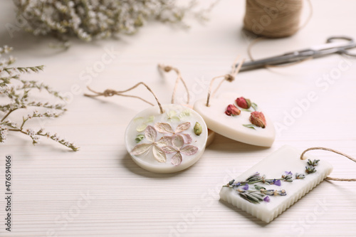 Scented sachets and flowers on white wooden table