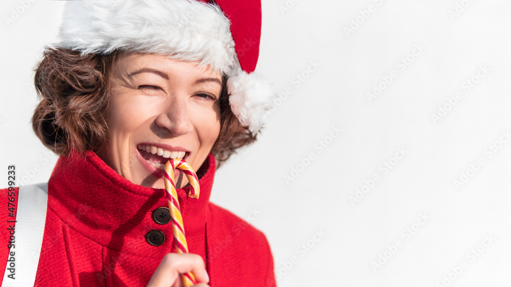 Curly winking woman with striped candy cane. Pretty female with Christmas licorice whip. Banner with copy space. Curly winking woman with striped candy cane. Pretty female with Christmas licorice whip. Banner with copy space.