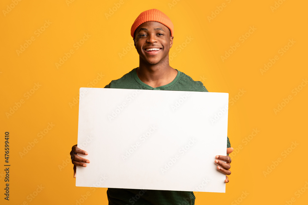 Cheerful Black Guy Holding White Blank Placard While Posing Over Yellow Background Cheerful Black Guy Holding White Blank Placard While Posing Over Yellow Background