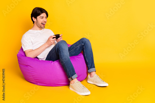 Portrait of attractive cheerful guy playing game having fun spending free time isolated over bright yellow color background