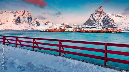 Red wooden pier on Gravdal bay. Frosty winter scene of popular tourist destination - Lofoten Islands archipelago. Amazing seascape of Norwegian sea. Stunning winter sunrise on Sakrisoy village. photo