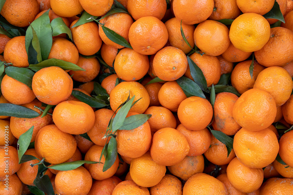 Fresh mandarin oranges fruit or tangerines with leaves, as background