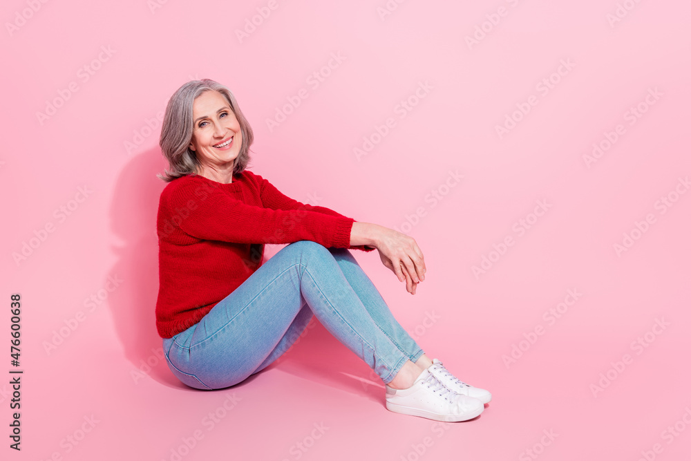 Portrait of attractive cheerful middle-aged grey-haired woman sitting resting free time isolated over pink pastel color background Portrait of attractive cheerful middle-aged grey-haired woman sitting resting free time isolated over pink pastel color background