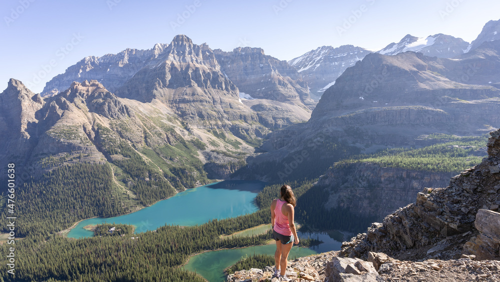 Female hiker enjoying beautiful view on alpine valley with glacial lakes surrounded by mountains