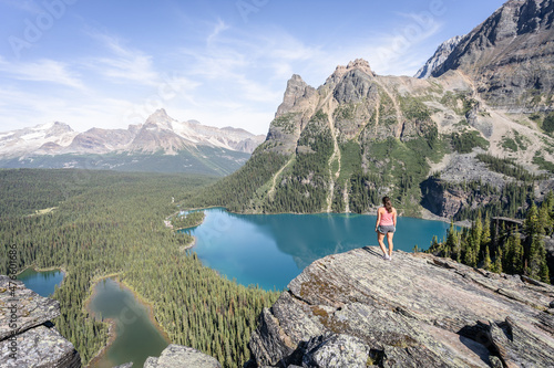 Female hiker enjoying beautiful view on alpine valley with glacial lakes surrounded by mountains