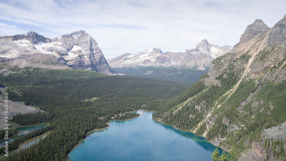 Beautiful alpine valley with blue glacier lake, forest and surrounding peaks, narrow shot, Canada