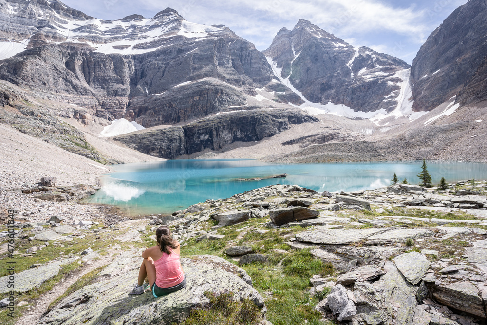 Female hiker sitting on the bank of turquoise glacier lake in beautiful alpine environment