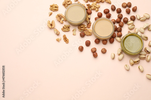 Different types of delicious nut butters and ingredients on beige background, flat lay. Space for text