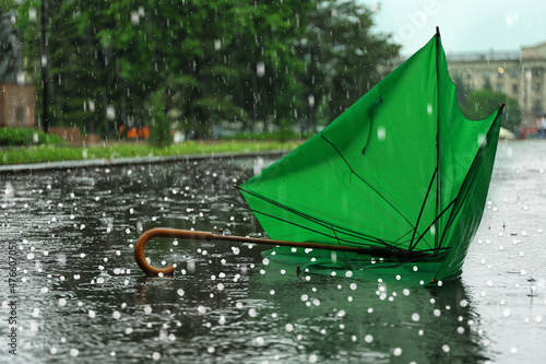 Canvastavla Broken green umbrella in park on rainy day with hail