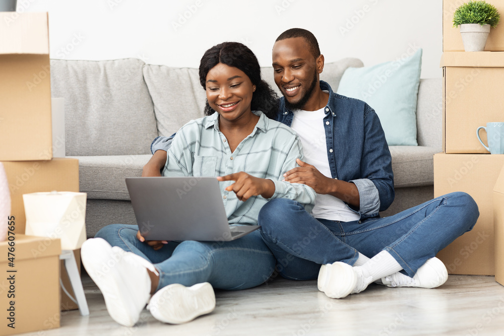 Black Couple With Laptop Sitting On Floor In New Flat After Moving
