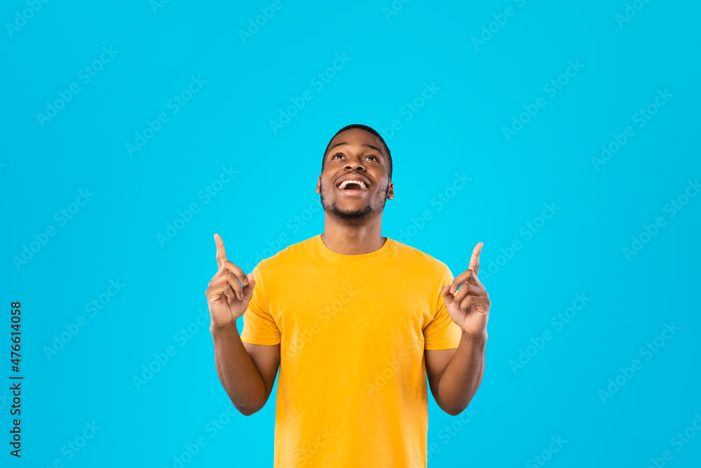 African Guy Pointing Fingers Up Looking Upward Over Blue Background African Guy Pointing Fingers Up Looking Upward Over Blue Background