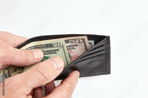 A man takes money out of a black leather wallet. The concept of financial security.