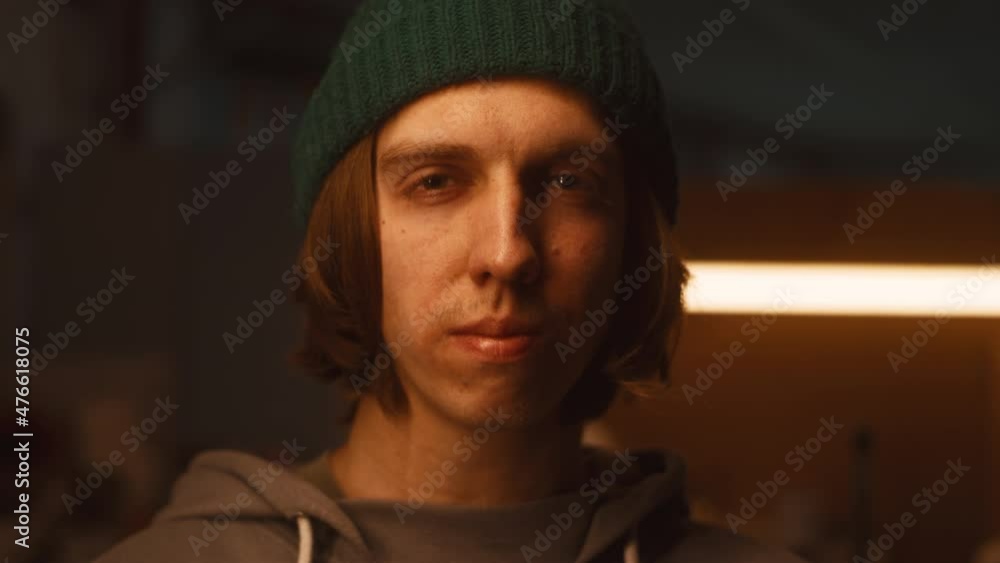 Young craftsman in hoodie and hat looking at camera while standing in dimly illuminated sculpting studio Young craftsman in hoodie and hat looking at camera while standing in dimly illuminated sculpting studio