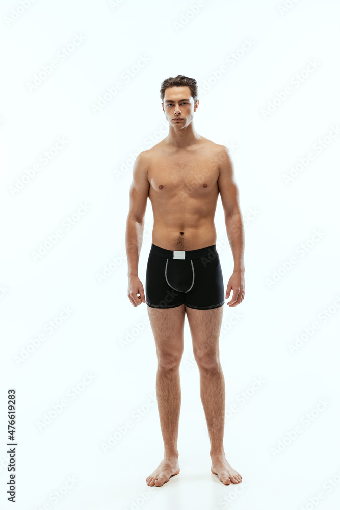 Full-length portrait of young handsome shirtless sportive man wearing black boxer-briefs standing isolated on white studio background. Full-length portrait of young handsome shirtless sportive man wearing black boxer-briefs standing isolated on white studio background.