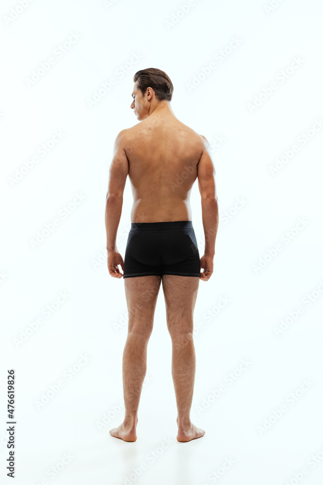 Back view of young handsome shirtless sportive man wearing black boxer-briefs standing isolated on white studio background. Back view of young handsome shirtless sportive man wearing black boxer-briefs standing isolated on white studio background.